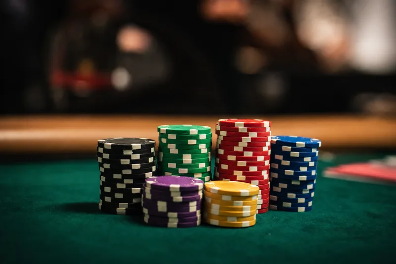 Stylised close-up photo of a modest tournament chip stack on green felt with a blurred rail of spectators in the background, illustrating a Day 1B stack around the Main Event average of 82,000 chips